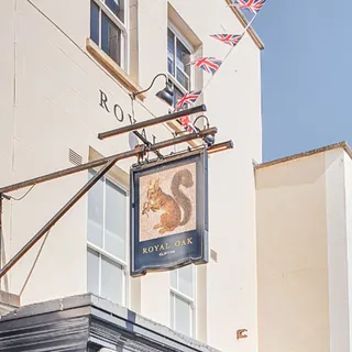 Photo of a building with a publican sign of a squirrel wearing a crown, with 'Royal Oak' written below it.
